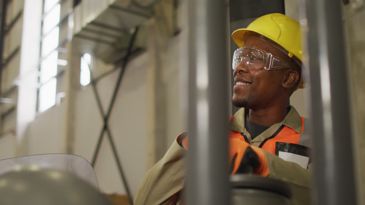 African american male worker wearing safety suit with helmet talking in warehouse