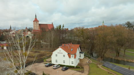 White-house-near-a-castle-and-bare-trees-in-Olsztyn,-Poland