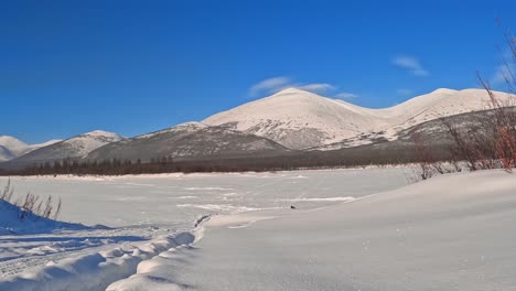 inmersión en la magia de la naturaleza invernal: un río congelado y majestuosas montañas nevadas envueltas en nubes