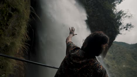 Male-With-Hand-Reaching-Toward-Pailon-Del-Diablo-Waterfall-In-Baños-De-Agua-Santa,-Ecuador---Closeup