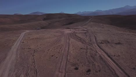 car driving on a dusty road in the atacama desert with an arid landscape in northern chile, south america