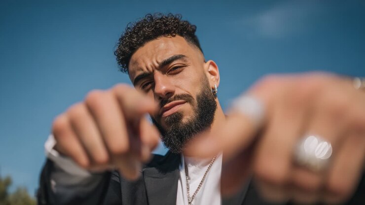 A Confident Individual Gesturing Towards the Camera with an Engaging Expression in a Bright, Outdoor Setting