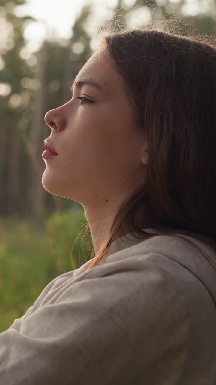 una mujer descansa cerca del tronco de un árbol en el bosque al atardecer. una joven siente el vacío con ansiedad pensando en maneras de mejorar la salud mental. encontrar el sentido de la vida