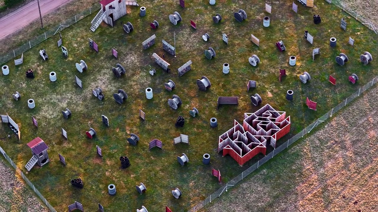 Campo da paintball o laser tag che mostra attività di gioco, ostacoli e un labirinto con bunker multipli.