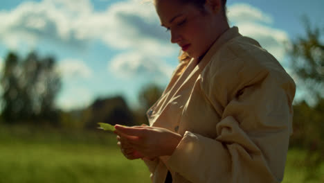 woman in a field, holding a leaf