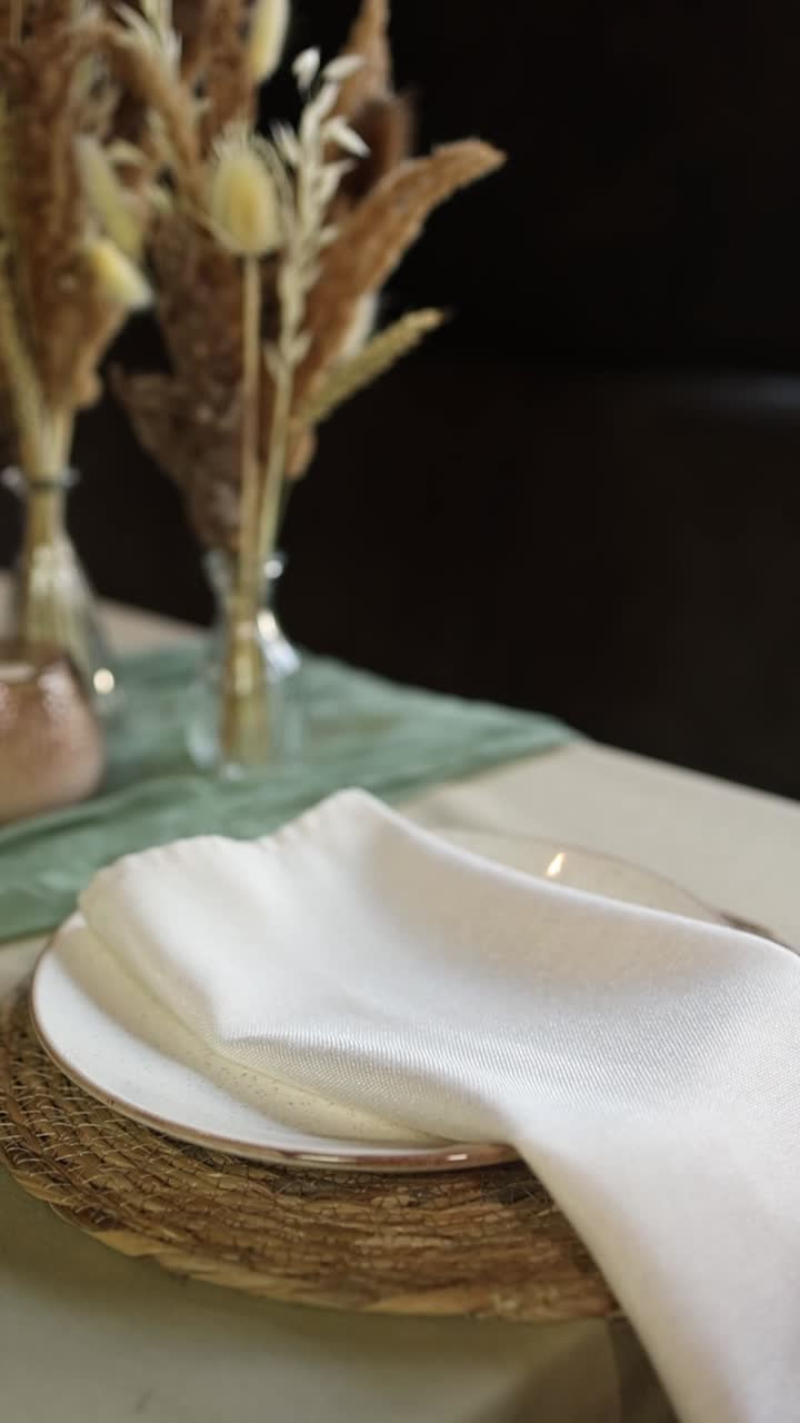 Hand Placing a White Napkin on an Elegant Dining Table Setting