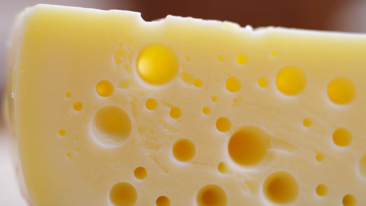 Close Up Swiss Cheese With Holes Golden Emmental Slice Showcasing Porous Texture, Glossy Eyes And Creamy