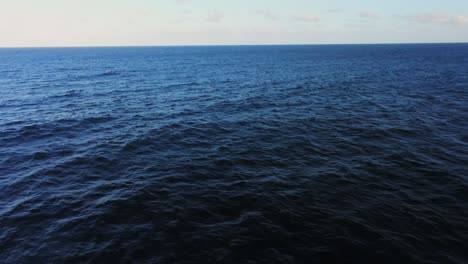 Vibrant-dark-blue-color-ocean-water-with-endless-horizon,-aerial-fly-backward-view