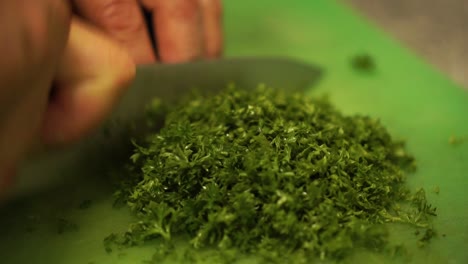 Chef-cutting-parsley-with-a-knife-on-a-cuttingboard