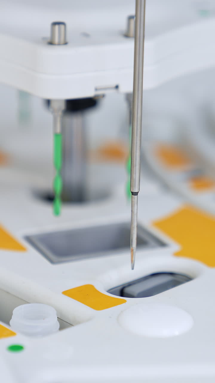 Metal needle lowering and deepening into the slots at machine. Close up. Advanced equipment carrying on medical testing. Blurred backdrop. Vertical video