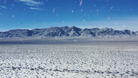 mountain range and winter desert during snowfall, aerial drone view