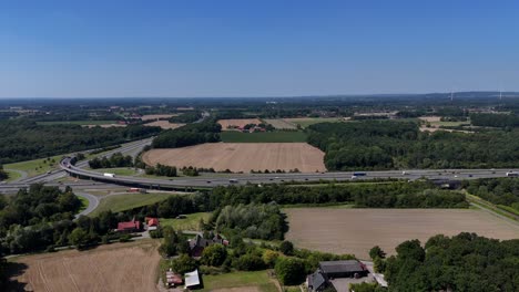 american highway with farmsteads during sunny summer day. junction with exit and ramps. pennsylvania state in rural countryside. aerial wide shot. lateral shot. busy traffic scene