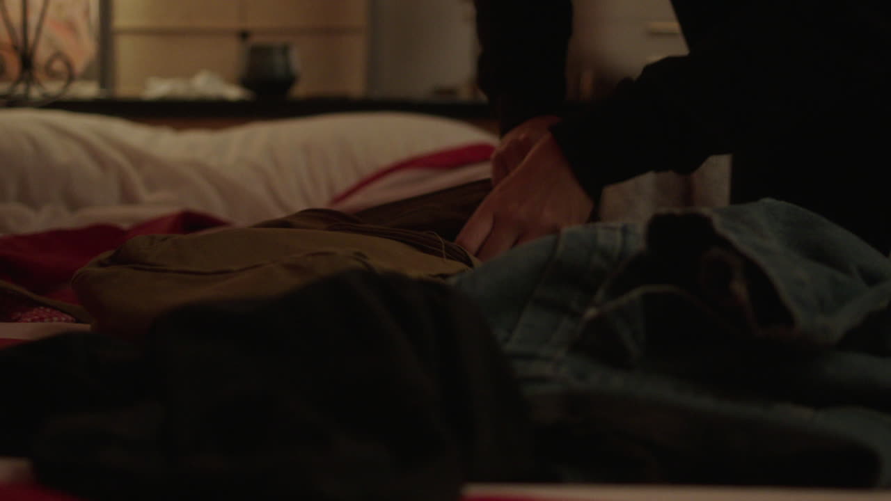 Person packing a backpack on a bed