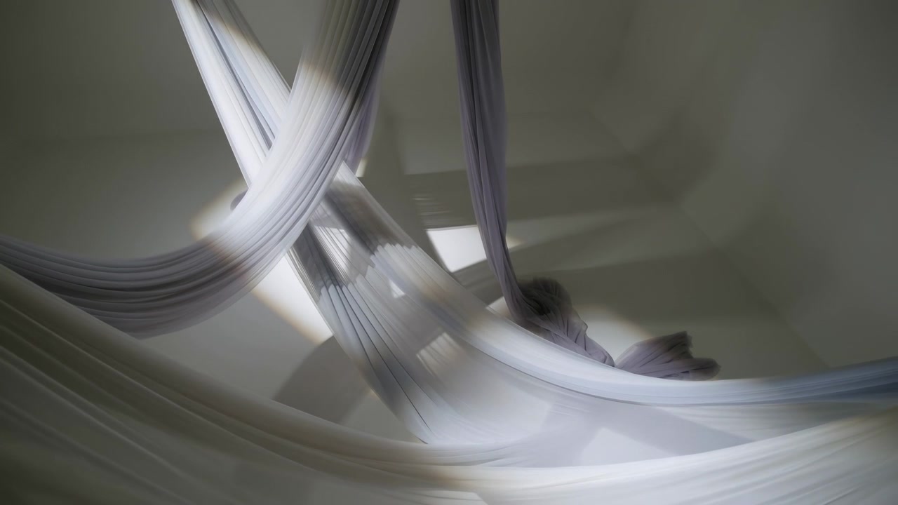 Wide interior view of suspended pleated fabric installation with semi-sheer panels draped from ceiling points into crossed loops, gathered folds, layered texture, soft shadows, and calm neutral tones
