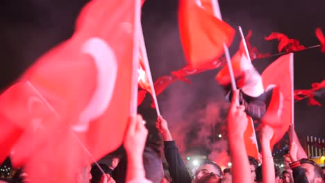 crowd of people waving turkish flags at night