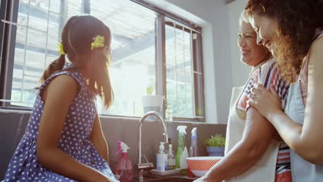 Girl-and-mother-looking-at-grandmother-washing-dishes-4K-4k