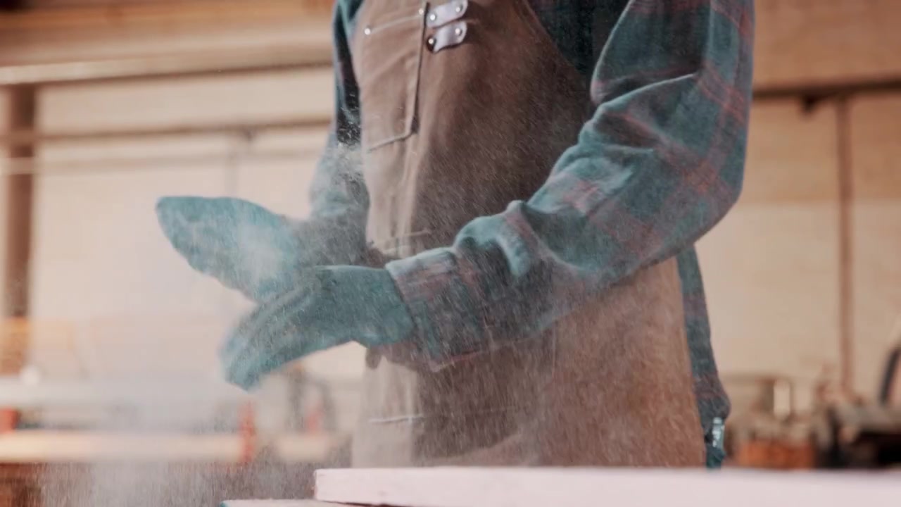 Carpenter Clapping Hands to Remove Sawdust in Workshop