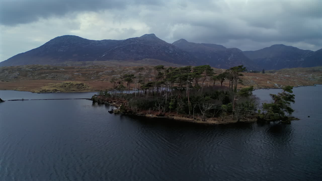 Gentle aerial orbit of Pine Island at twilight, with dramatic skies and mountains, Connemara