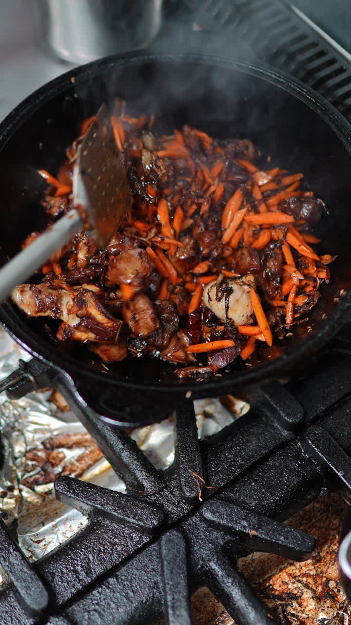 Cooking meat and carrots in a cast iron wok