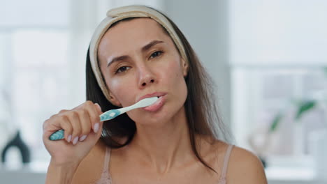 awaking woman cleaning teeth at bathroom closeup. serious lady dental hygiene