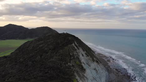 Aerial-of-beautiful-scenic-New-Zealand-landscape-and-historic-landmark,-East-Cape-Lighthouse