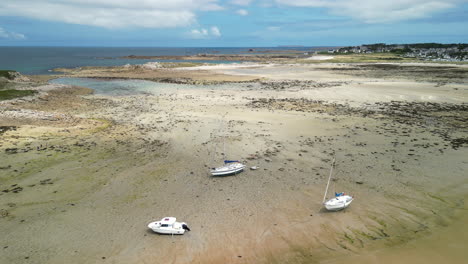 Downward-Dolly-Aerial-of-Three-Small-Boats-Resting-on-Sandy-Beach-at-Low-Tide