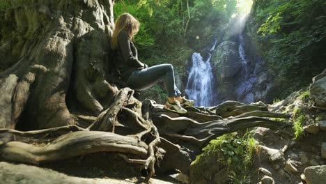 caucasian beautiful woman sitting on old tree roots in nature