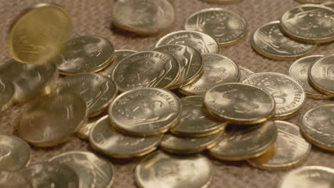 indian currency golden 5 rupee coins falling on jute gunny textured cloth, 4k, stable shot