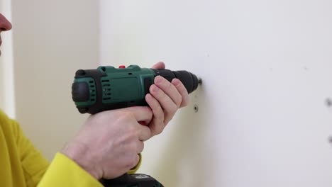 person drilling into a wall with a cordless drill