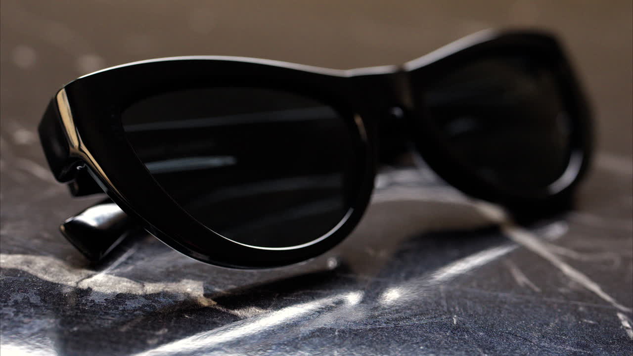Close up of a black pair of sunglasses on a black surface