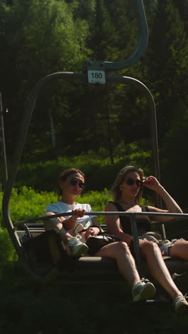 young women ride cable car down hilly mountain and enjoy view of dense forest. getting closer to nature and enjoying holiday at tourist destination