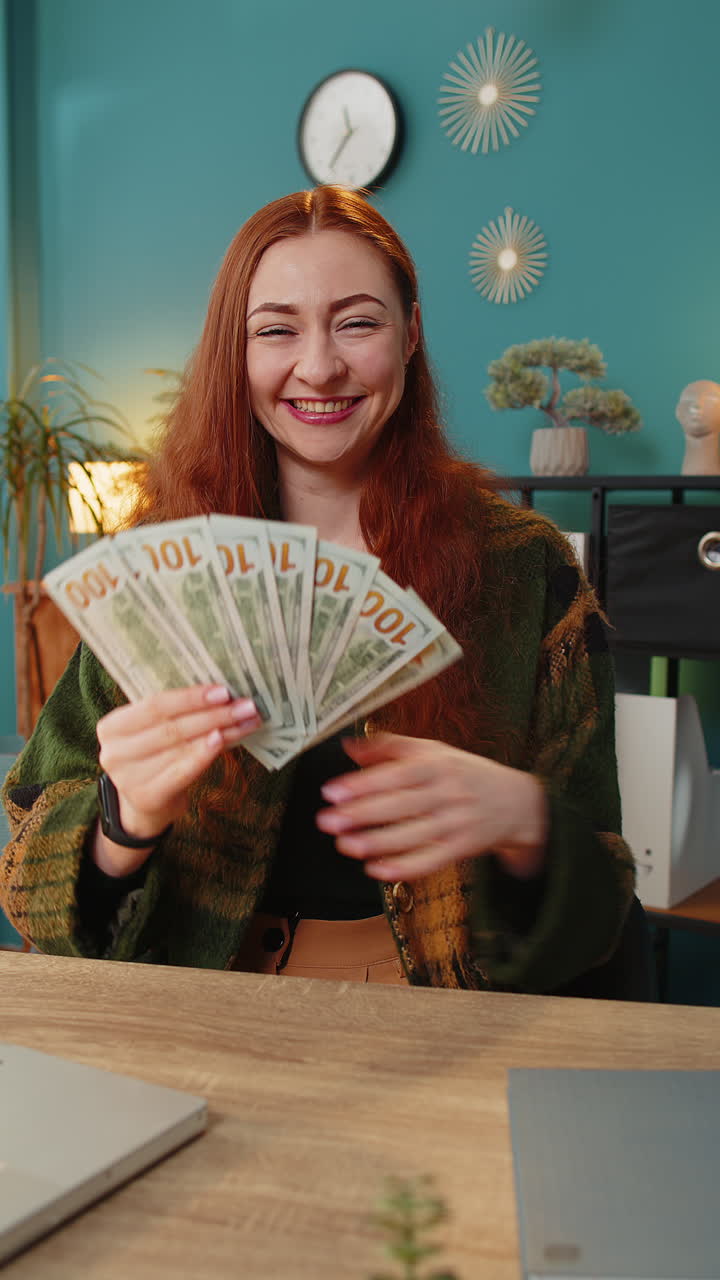 Rich redhead woman winner waves money dollar cash like fan big income wealth success business salary