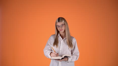 una mujer rubia atractiva pensó en la pregunta y encontró la respuesta, escribiendo notas en un cuaderno de papel, toma de estudio