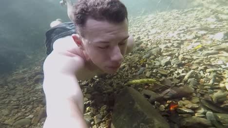 adult shirtless male swimming underwater at stoney creek, cairns