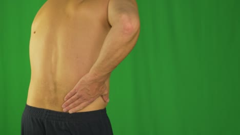 hombre frotando con la palma de la mano la parte inferior de la espalda debido al dolor de espalda.