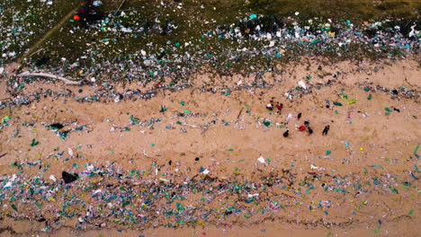 aerial top view of children playing on the beach completely full of plastic bags