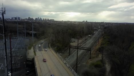 railroad track underneath highway bridge full of cars, drone tracking shot