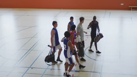 Diverse-male-basketball-team-and-coach-high-fiving-after-match