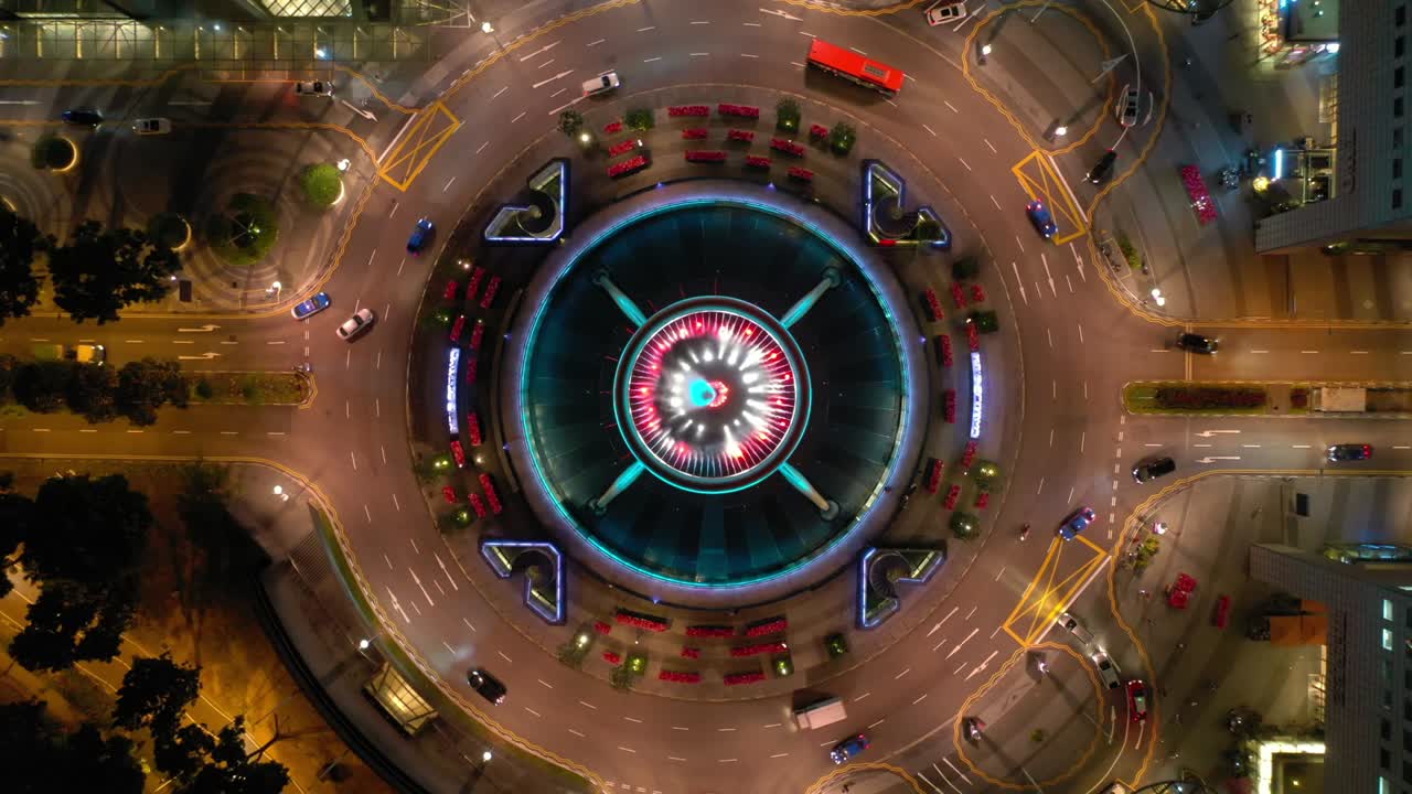 vuelo de iluminación nocturna sobre la ciudad de singapur famoso círculo de tráfico del centro panorámica aérea de arriba hacia abajo 4k