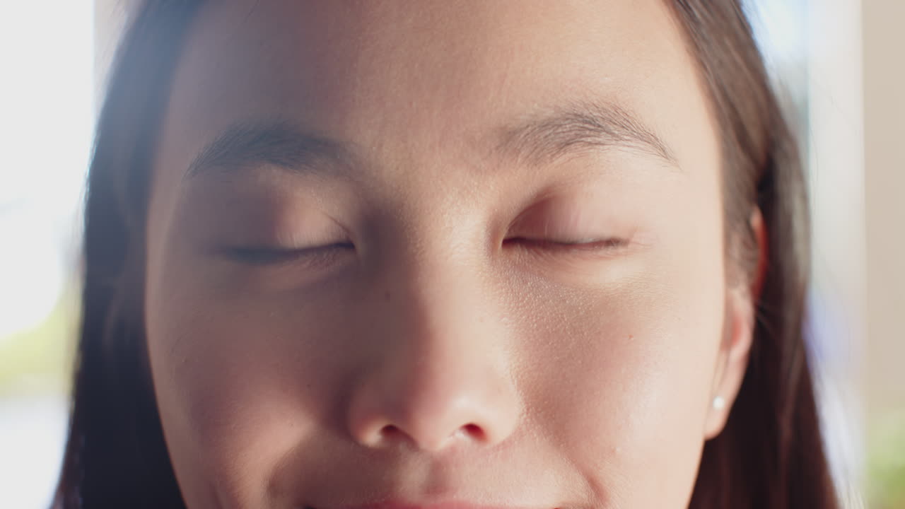 Smiling asian teenage girl with one eye closed, close-up portrait in natural light, copy space
