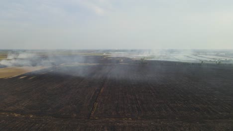 aerial footage towards charred farmlands already tilled and this is air pollution, grassland burning, pak pli, nakhon nayok, thailand