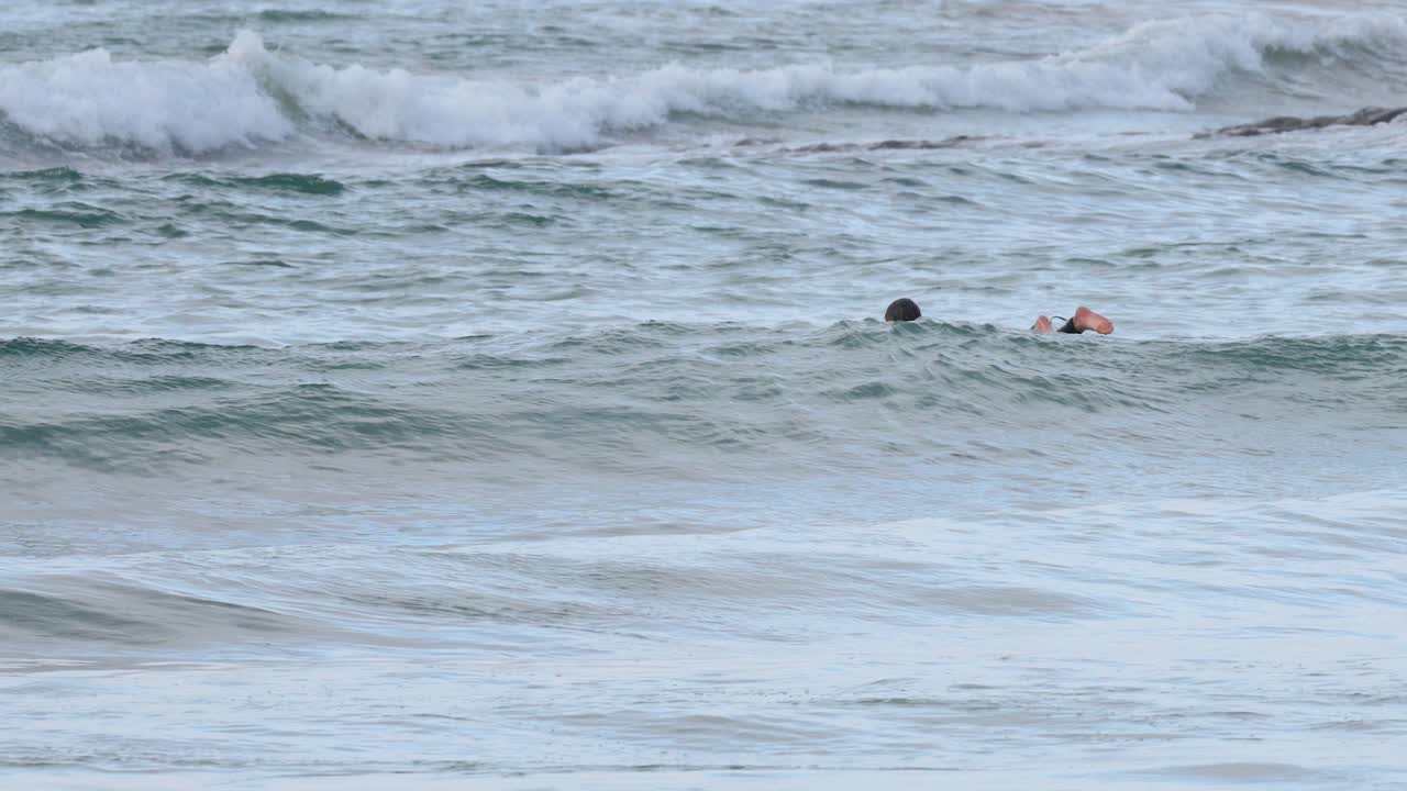 Surfer paddling through waves in ocean waters