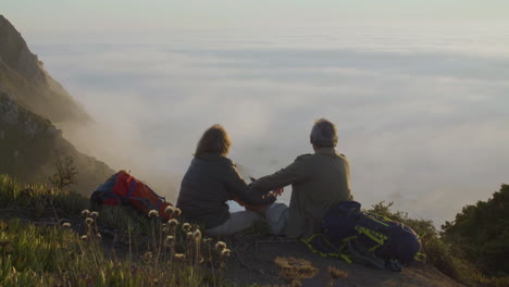 senior couple sitting on top of mountain and kissing