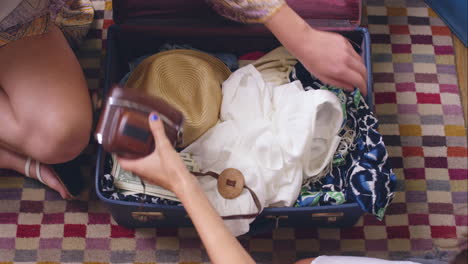 Top-view-packing-vintage-suitcase-girls-planning-road-trip