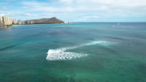 Aerial-view-of-surfer-off-coast-of-Waikiki-with-diamond-head-and-hotels-in-background