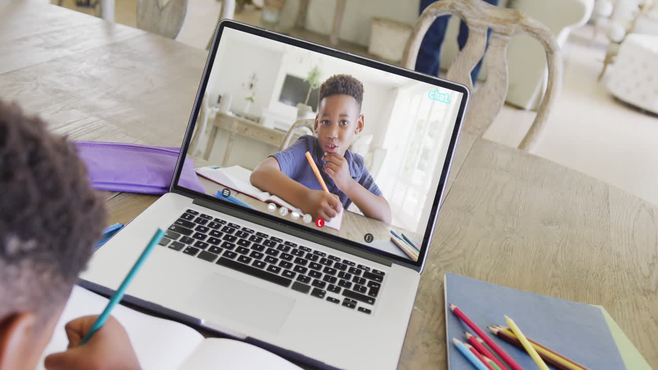 African american boy using laptop for video call with african american school friend on screen