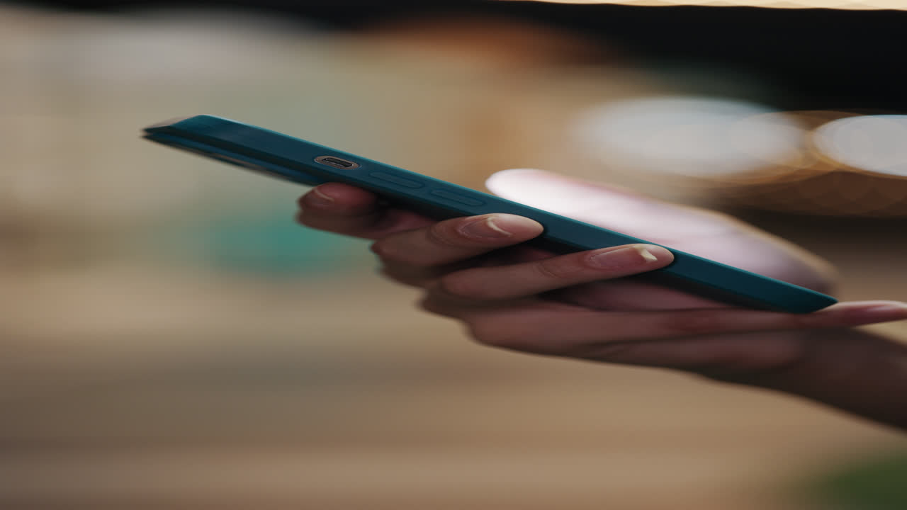 Person holding a teal colored smartphone at night