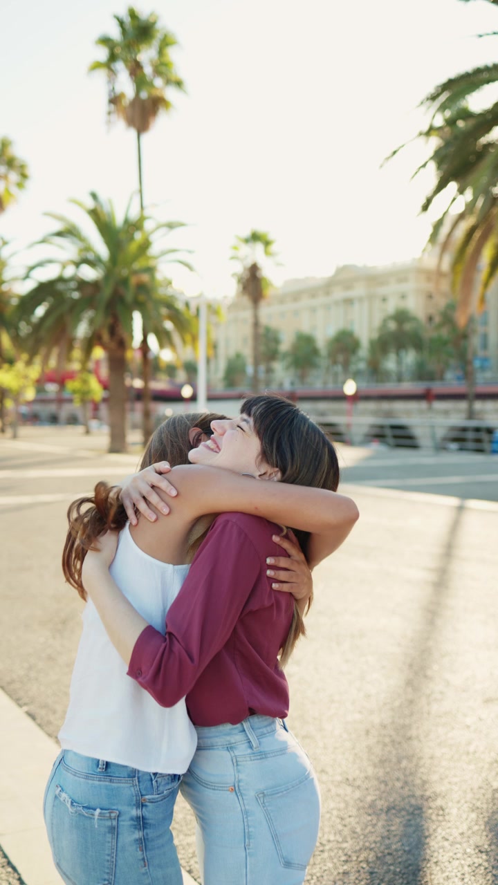 Due amiche felici che si abbracciano in una strada cittadina soleggiata