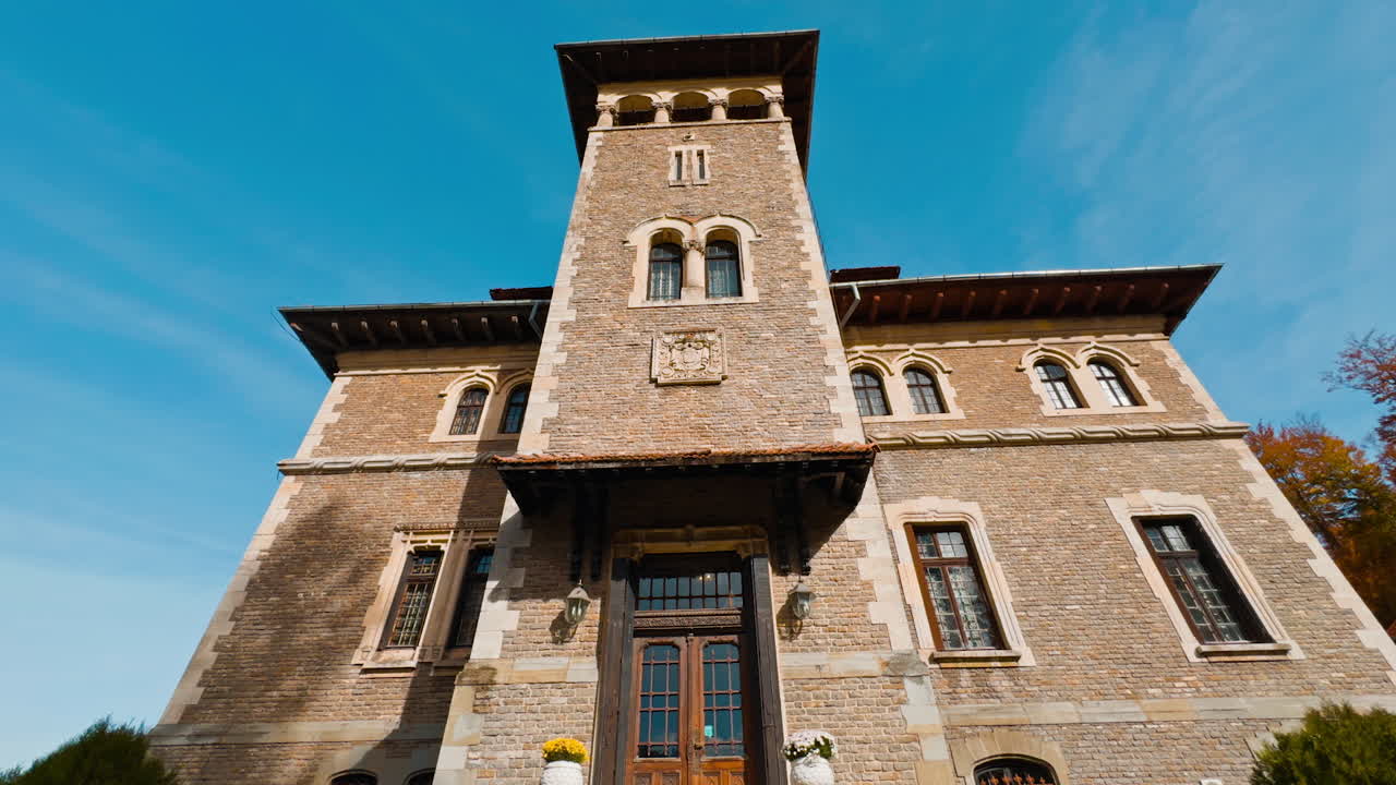 At the staircase to the old beautiful palace with tower. Cantacuzino Castle in Busteni, Romania on sunny day. Low angle view.
