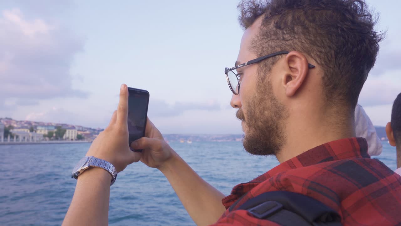 hombre viendo el bósforo y la ciudad desde el ferry por teléfono.